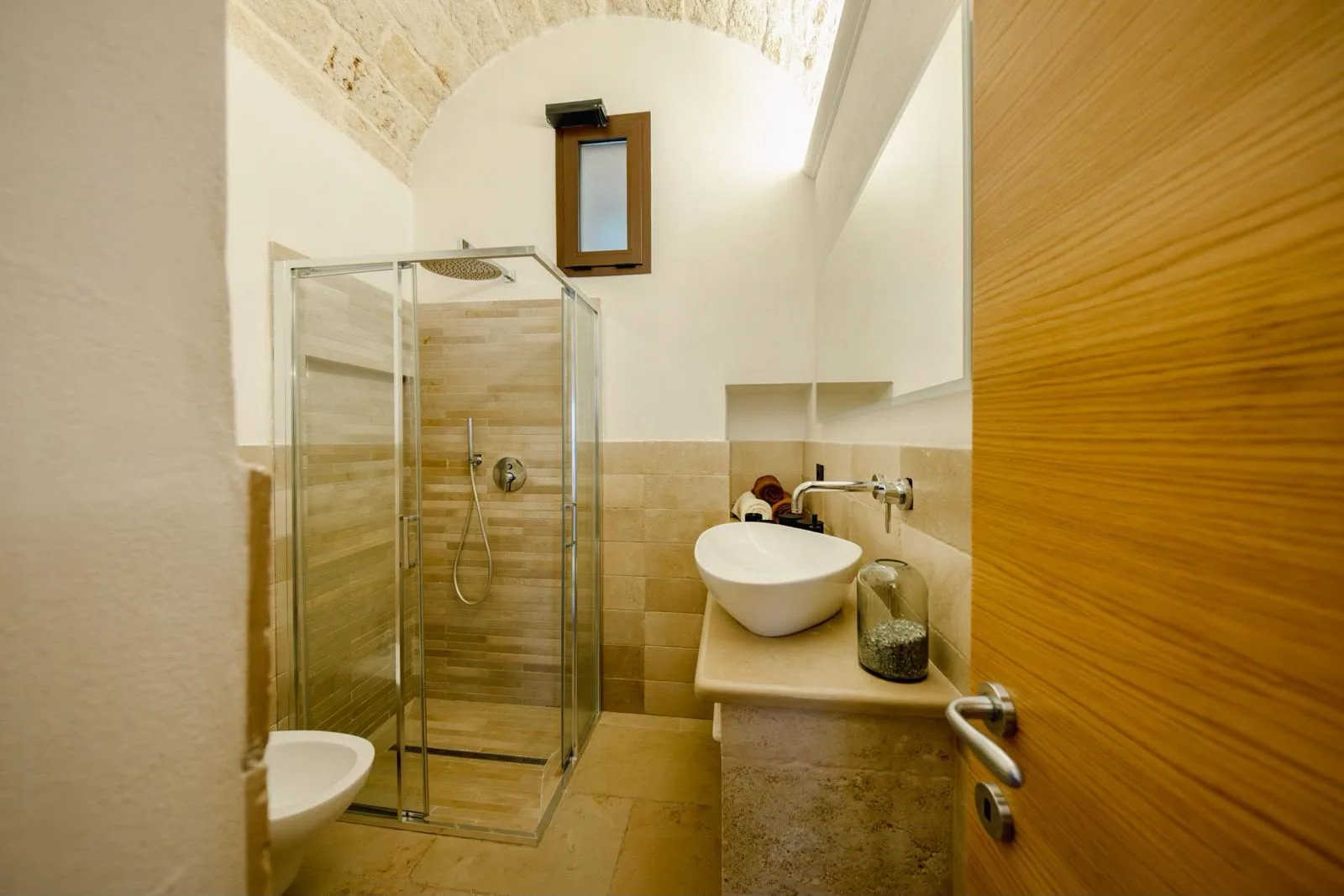 Bagno con doccia in vetro e lavabo in pietra