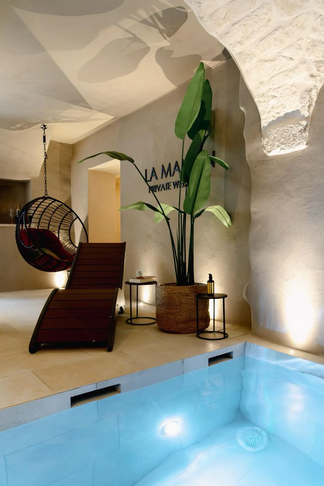 Zona relax con lettino e poltrona sospesa accanto alla piscina